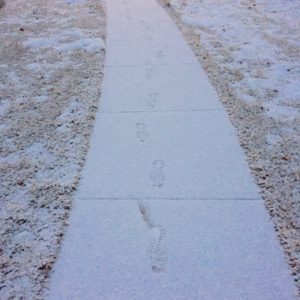 Footprints in the snow on the sidewalk.